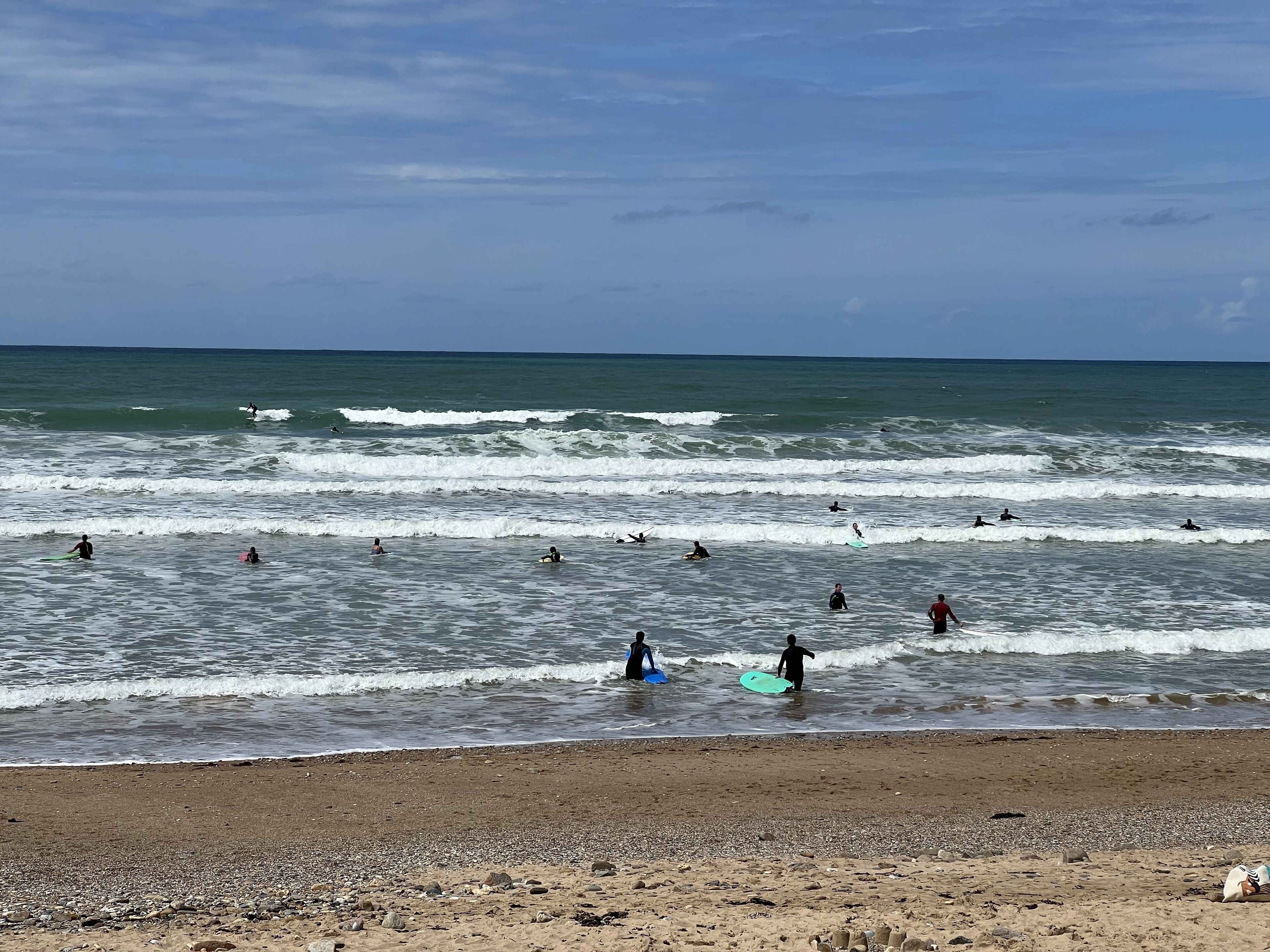 Une plage où l’on peut voir des gens faire de la planche à voile et nager dans l’océan.