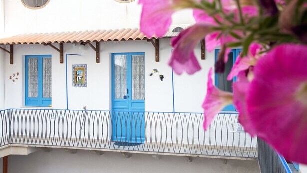 Un edificio con facciata bianca, porte blu e un balcone con ringhiera in metallo.
