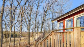 Une terrasse en bois avec un escalier menant à un bâtiment doté de grandes fenêtres.