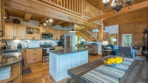 A spacious kitchen with wooden cabinets, a central island, and a dining area with a table and chairs. - Range Views - 2 BR w/Sleep Loft, Hot Tub, Firepit at Maggie Valley Club (Maggie Valley)