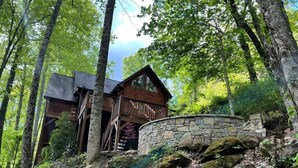 A cabin with a stone foundation, wooden exterior, and a balcony overlooking a forested area. - Range Views - 2 BR w/Sleep Loft, Hot Tub, Firepit at Maggie Valley Club (Maggie Valley)