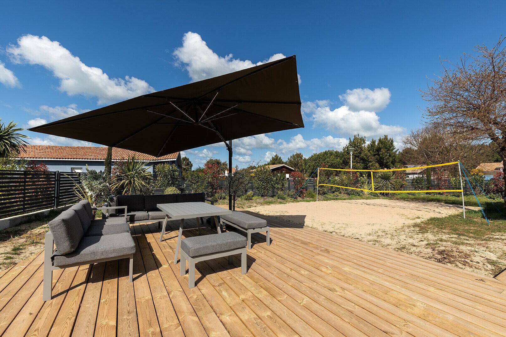 Eine Holzterrasse mit Gartenmöbeln und einem Volleyballnetz.