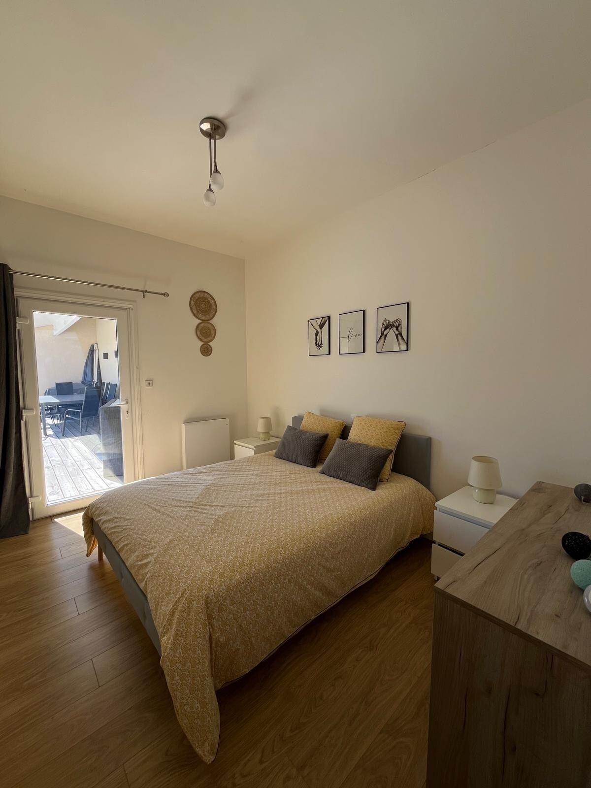 Une chambre à coucher comprenant un lit, des tables de chevet, un bureau et un ventilateur de plafond.