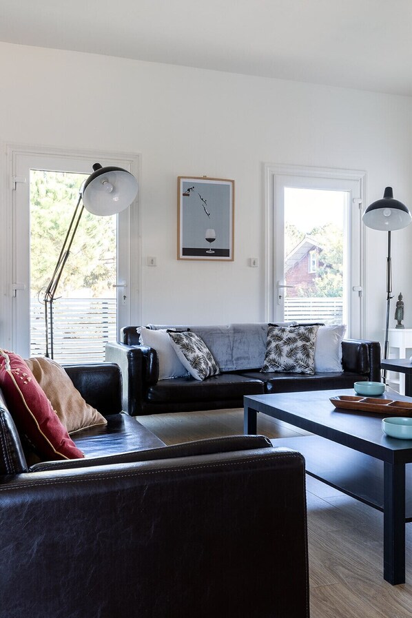 Un salon avec un canap é en cuir noir, une table basse en bois et un tableau accroché au mur.