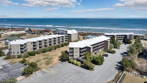 Un quartier résidentiel situé sur la côte, avec des immeubles à plusieurs étages, un parking et une vue sur l’océan.