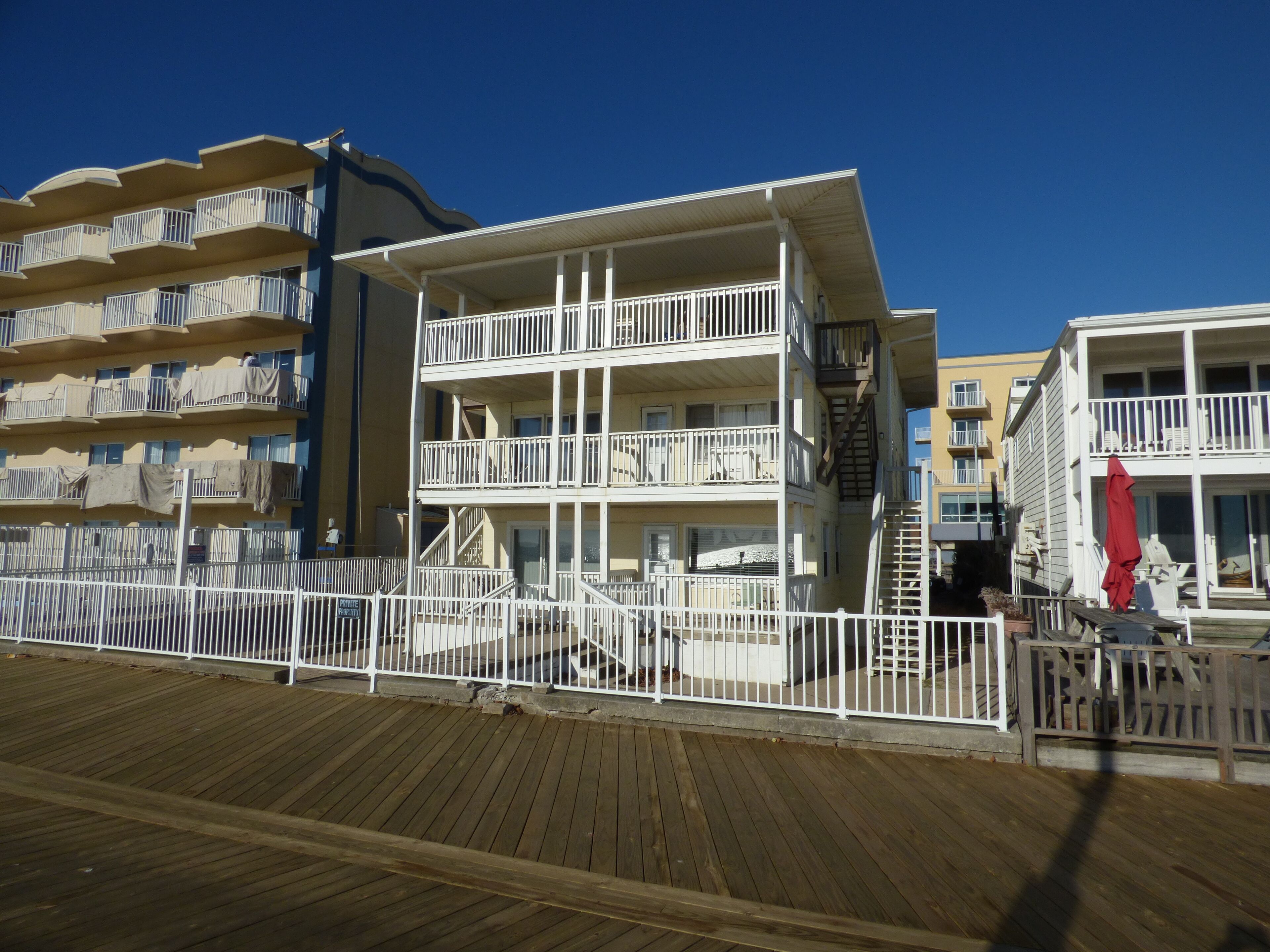 Um hotel com vários andares, varandas, um deck de madeira e uma área cercada.