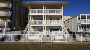 Een meerlaags gebouw met balkons en een houten terras ervoor.