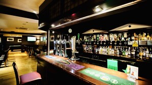 Una zona de bar con múltiples grifos, un reloj y una variedad de botellas de licor.