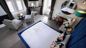 A hotel room with a bed, a desk, a chair, a TV, and a window.
