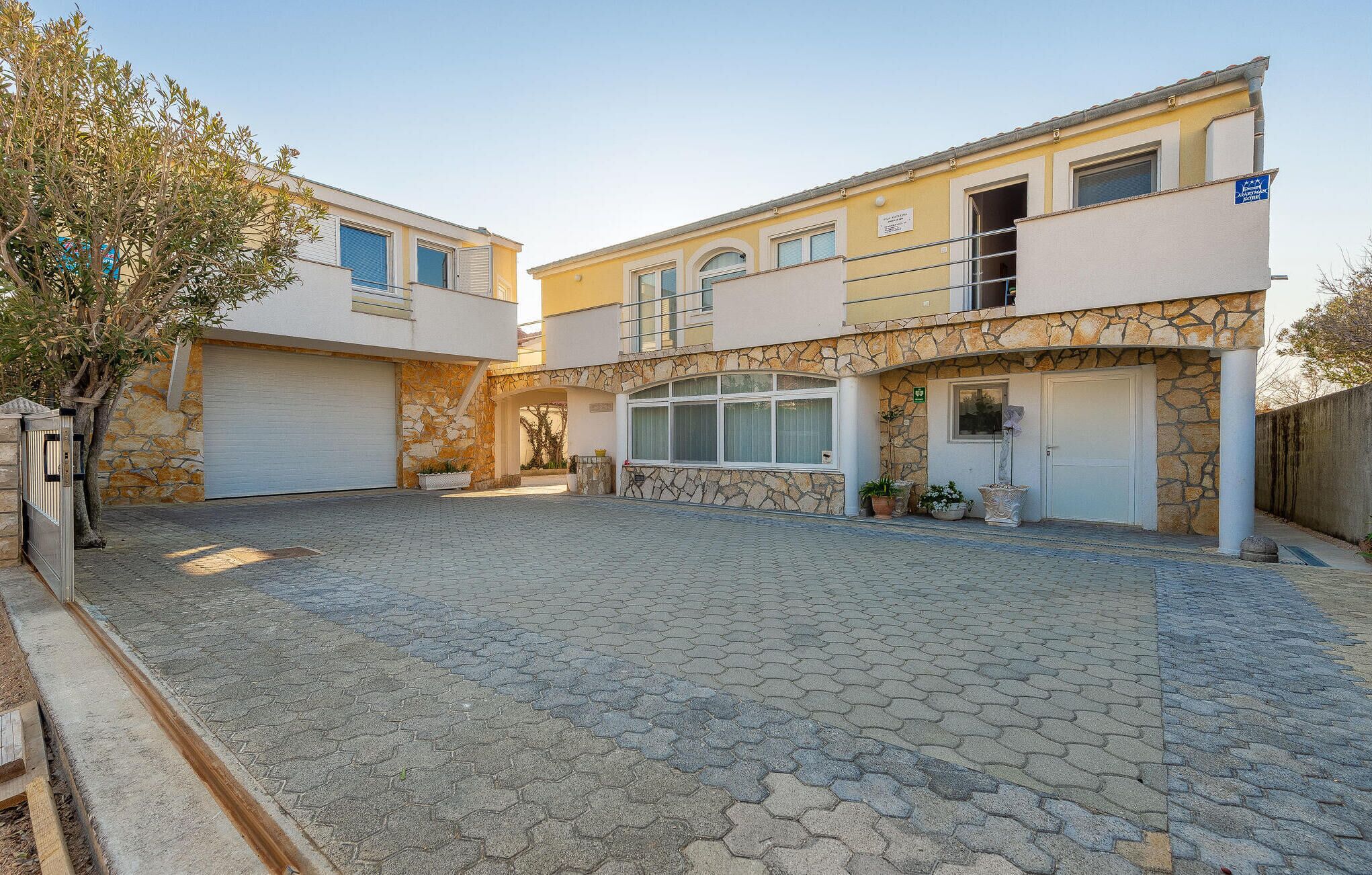 A two-story building with a stone facade, a covered patio area, and a garage.