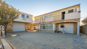 A two-story building with a stone facade, a covered patio area, and a garage. - Amazing apartment in Nin with WiFi (Nin)