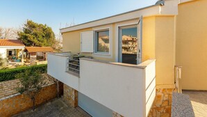 A residential building with a balcony, a stone wall, and a small garden area. - Amazing apartment in Nin with WiFi (Nin)