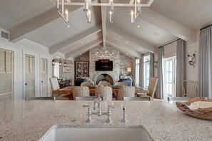 A spacious kitchen with a granite countertop, a built-in oven, and a dining area with wicker chairs. - Gulf-Front Home, Panoramic Views, Resort-Style Amenities in Cinnamon Shore (Port Aransas)