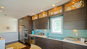 A modern kitchen with dark cabinetry, stainless steel appliances, and a blue backsplash. - Simply The Best - At Angler's Nest! (Lewes)