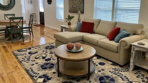 Ein Wohnzimmer mit einem beigefarbenen Ecksofa, einem runden Couchtisch und einem gemusterten Teppich.
