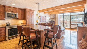A spacious kitchen with wooden cabinets, a large island with bar stools, a microwave, and a fireplace. - Perfect view of Super Bee, ski-in/out, wonderful sunlight, free WiFi, parking (Copper Mountain)