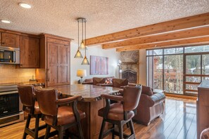Una cocina amplia con armarios de madera, una isla grande con taburetes de bar, una chimenea de piedra y vistas al exterior.