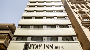 Een meerlaags hotel met een bord met de tekst 'STAY INN HOTEL' op de gevel.
