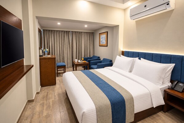 Une chambre d’hôtel équipée d’un lit, d’un bureau, d’une chaise, d’une télévision et d’un appareil de climatisation.