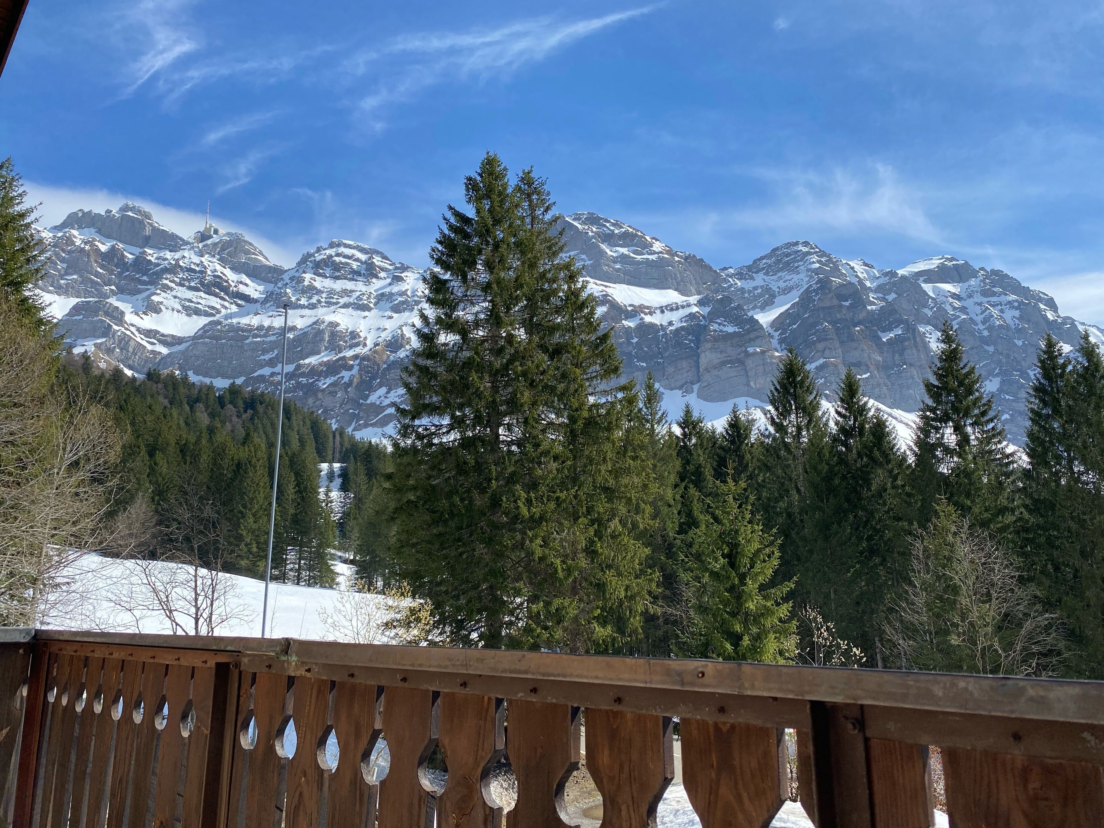 Blick auf Berge mit schneebedeckten Gipfeln und ein Holzboden im Vordergrund.