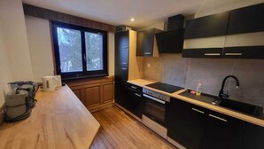 A modern kitchen with wooden cabinets, a black countertop, and a window providing natural light. - Apartment with garden at the foot of the Säntis (Urnäsch)