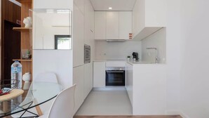 Una cucina moderna con mobili bianchi, forno a incasso e un piccolo piano di lavoro.