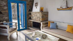 Uma sala de estar com lareira de pedra, uma mesa de centro de vidro e uma porta azul.