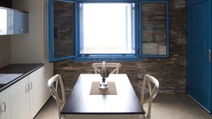 Uma cozinha com mesa, cadeiras, uma janela e uma porta azul.