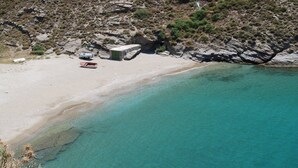 Uma praia com águas turquesa cristalinas, terreno rochoso e um pequeno barco.