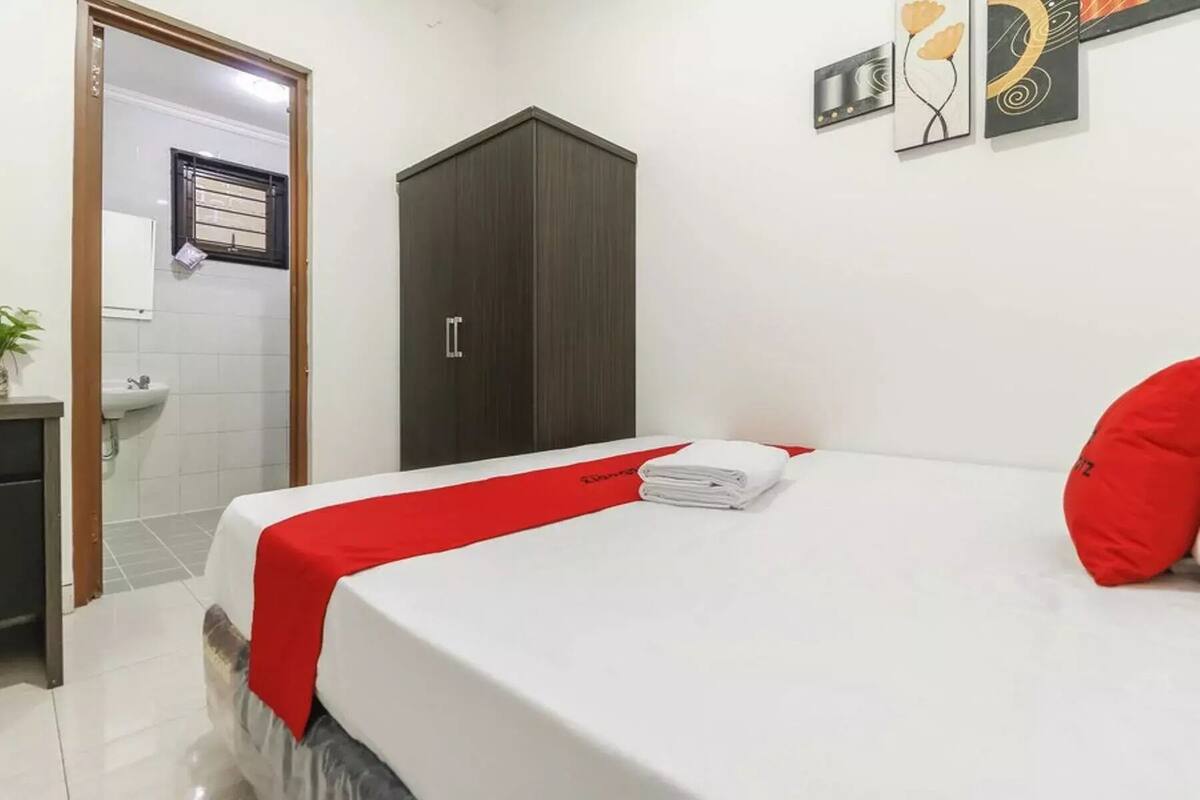 Une chambre d’hôtel comprenant un lit, une armoire, un lavabo et une porte donnant accès à la salle de bain.
