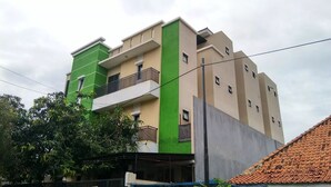 Ein mehrgeschossiges Wohngebäude mit einer grün-beigen Fassade, Balkonen und einer sichtbaren Stromleitung.