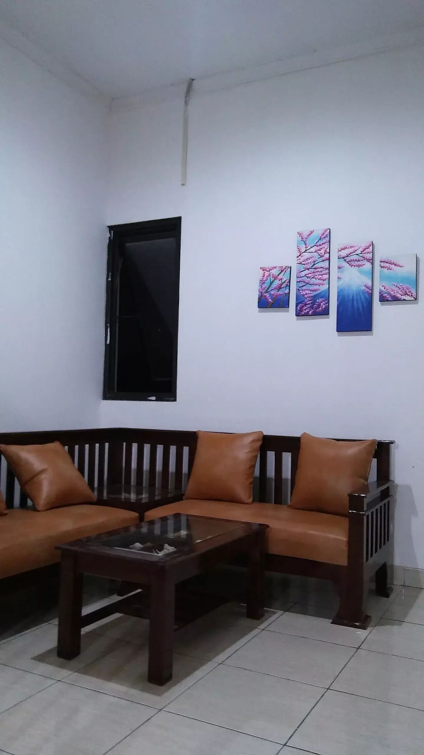 Un salon comprenant un canapé, une table basse et trois tableaux accrochés au mur.