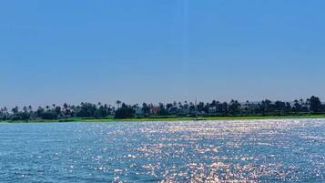 A calm body of water reflecting sunlight with a distant shoreline and greenery.