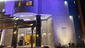 A modern building with a circular design, featuring multiple balconies and a well-lit entrance.