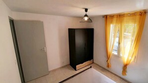 A room with a door, a black cabinet, a ceiling light fixture, and a window with yellow curtains. - T3 with pool 2mn from the beach (Pietracorbara)