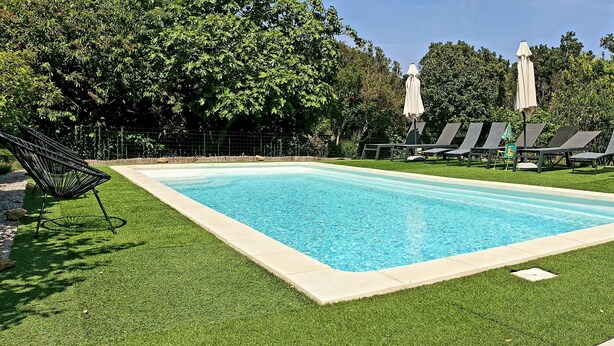 A rectangular swimming pool surrounded by artificial grass, with lounge chairs and umbrellas. - T3 with pool 2mn from the beach (Pietracorbara)