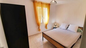 A bedroom with a bed, curtains, a bedside table, and a lamp. - T3 with pool 2mn from the beach (Pietracorbara)