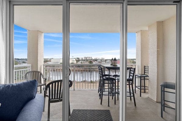 Enjoy the city view from this balcony with a sofa, chairs, and table.