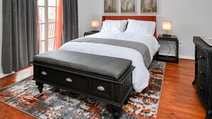 A bedroom with a bed, bedside tables, a bench, and artwork on the wall. - Condo in Midtown. One block from downtown. Minutes from Texas Medical Center  (Houston)