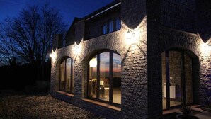 A stone building with arched windows and exterior lighting. - Casa Mestres - La Botiga (Pujalt)