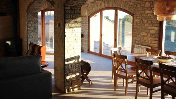 A rustic interior with stone walls, a wooden dining table, and chairs. - Casa Mestres - La Botiga (Pujalt)