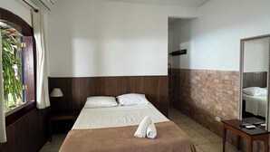 Una habitación de hotel con una cama, un espejo, una mesita de noche y una ventana con cortinas.