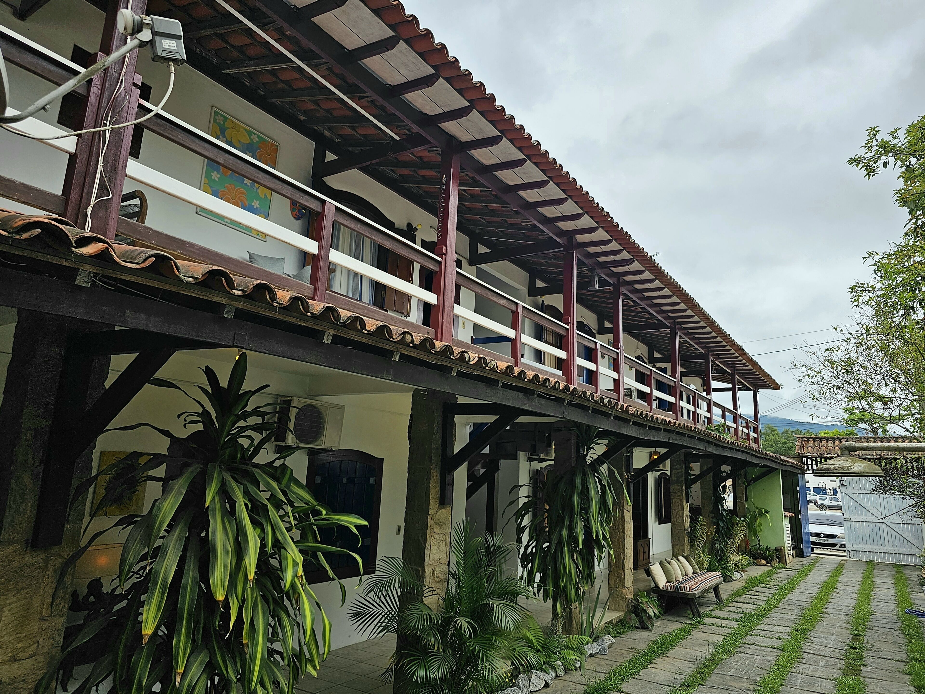 A two-story building with a balcony, outdoor seating, and potted plants.