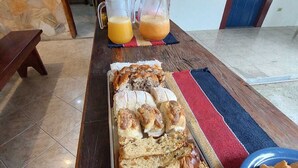 Un desayuno con una bandeja de pasteles, una jarra de zumo de naranja y una botella de leche sobre un suelo de baldosas.