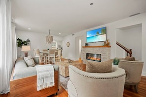A modern living room with a sofa, armchair, fireplace, TV, and a dining area. - Stay in A Castle In St. Augustine, Hot Tub, Fireplace (St. Augustine)