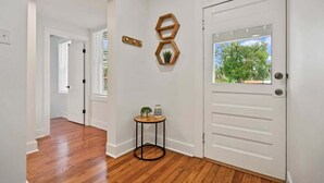 A hallway with wooden flooring, a white door, and a small round table with a plant and a lamp. - Stay in A Castle In St. Augustine, Hot Tub, Fireplace (St. Augustine)