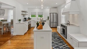 A modern kitchen with white cabinetry, a central island, stainless steel appliances, and a chandelier. - Stay in A Castle In St. Augustine, Hot Tub, Fireplace (St. Augustine)