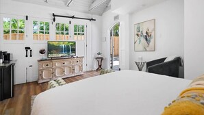 A bedroom with a large bed, a TV, a dresser, and a view of a wooden deck. - Stay in A Castle In St. Augustine, Hot Tub, Fireplace (St. Augustine)