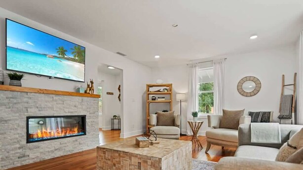 A living room with a fireplace, a flat-screen TV, a sofa, and a coffee table. - Stay in A Castle In St. Augustine, Hot Tub, Fireplace (St. Augustine)