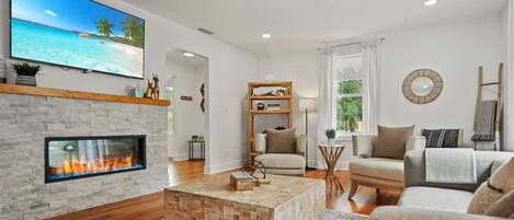 A living room with a fireplace, a flat-screen TV, a sofa, and a coffee table.